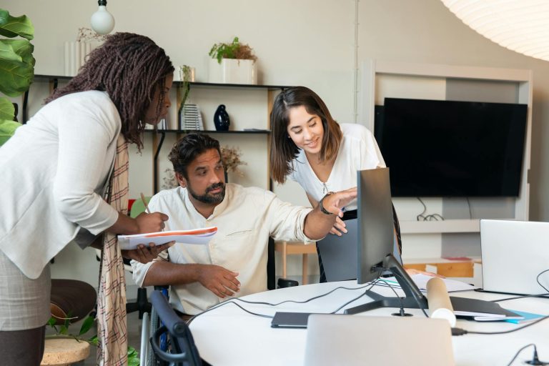 Diverse team engaged in collaborative discussion around computer in modern office.